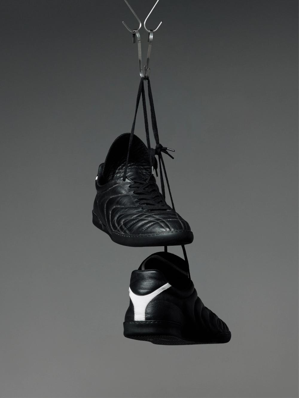 Black athletic shoes with a white Y logo hanging from a metal clip.