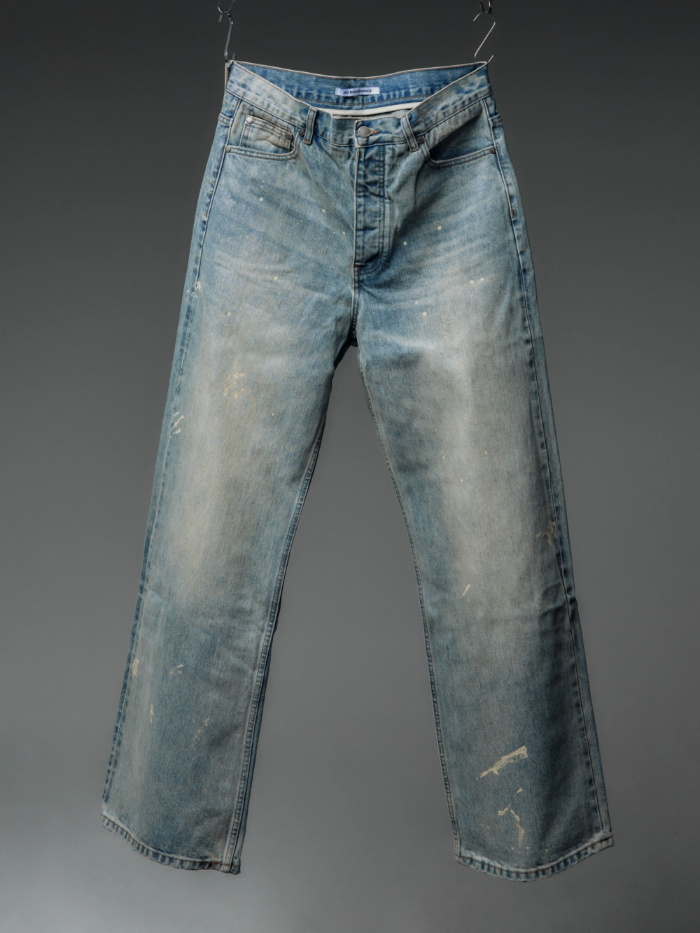 Faded light blue jeans with white paint splatters.