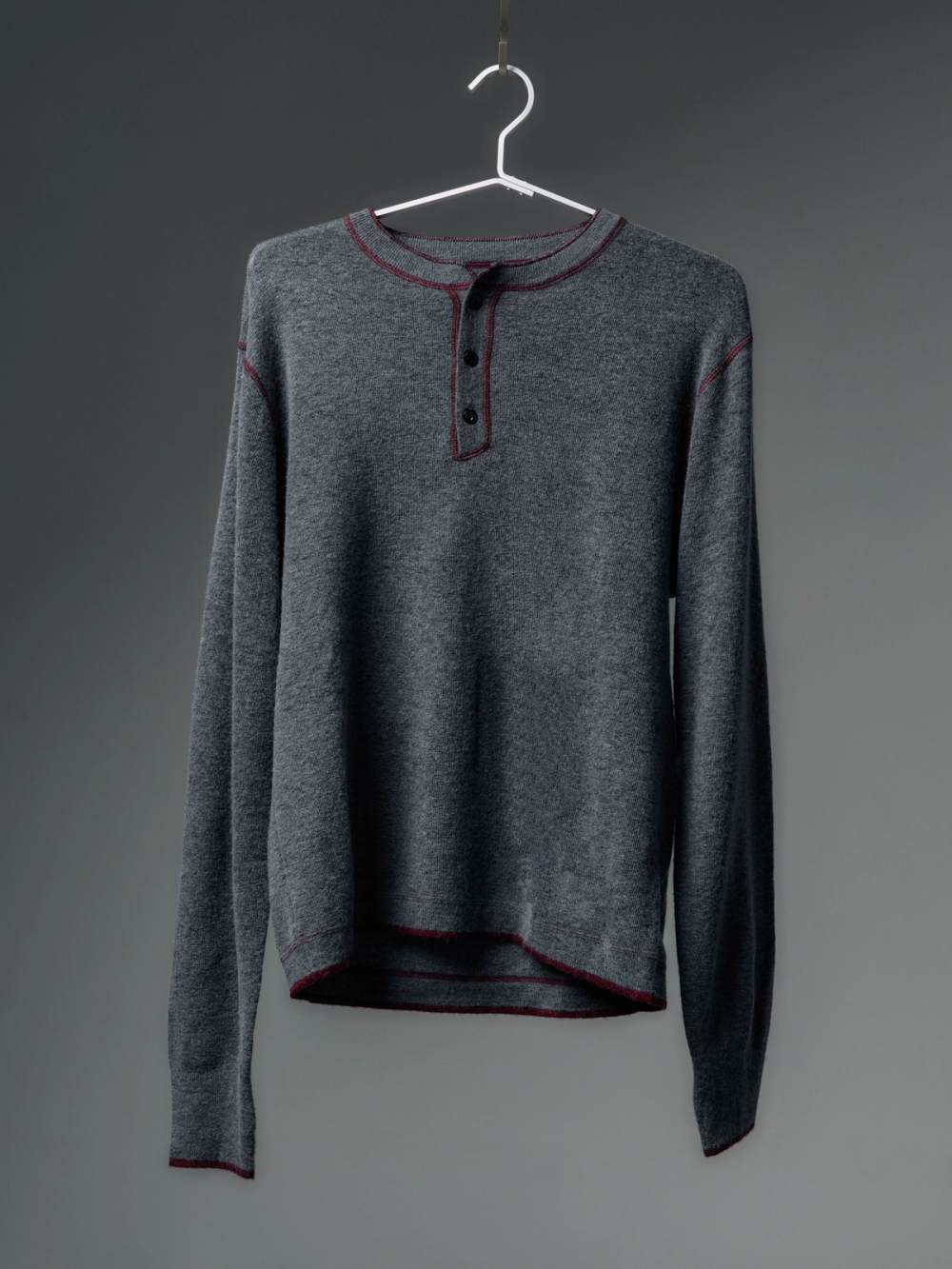 Gray long-sleeve shirt with red trim and three buttons hanging on a white hanger.