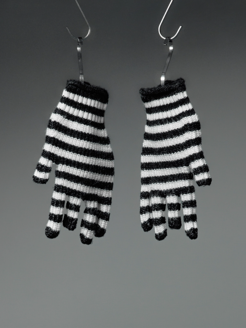 Two small black and white striped gloves hanging from hooks.