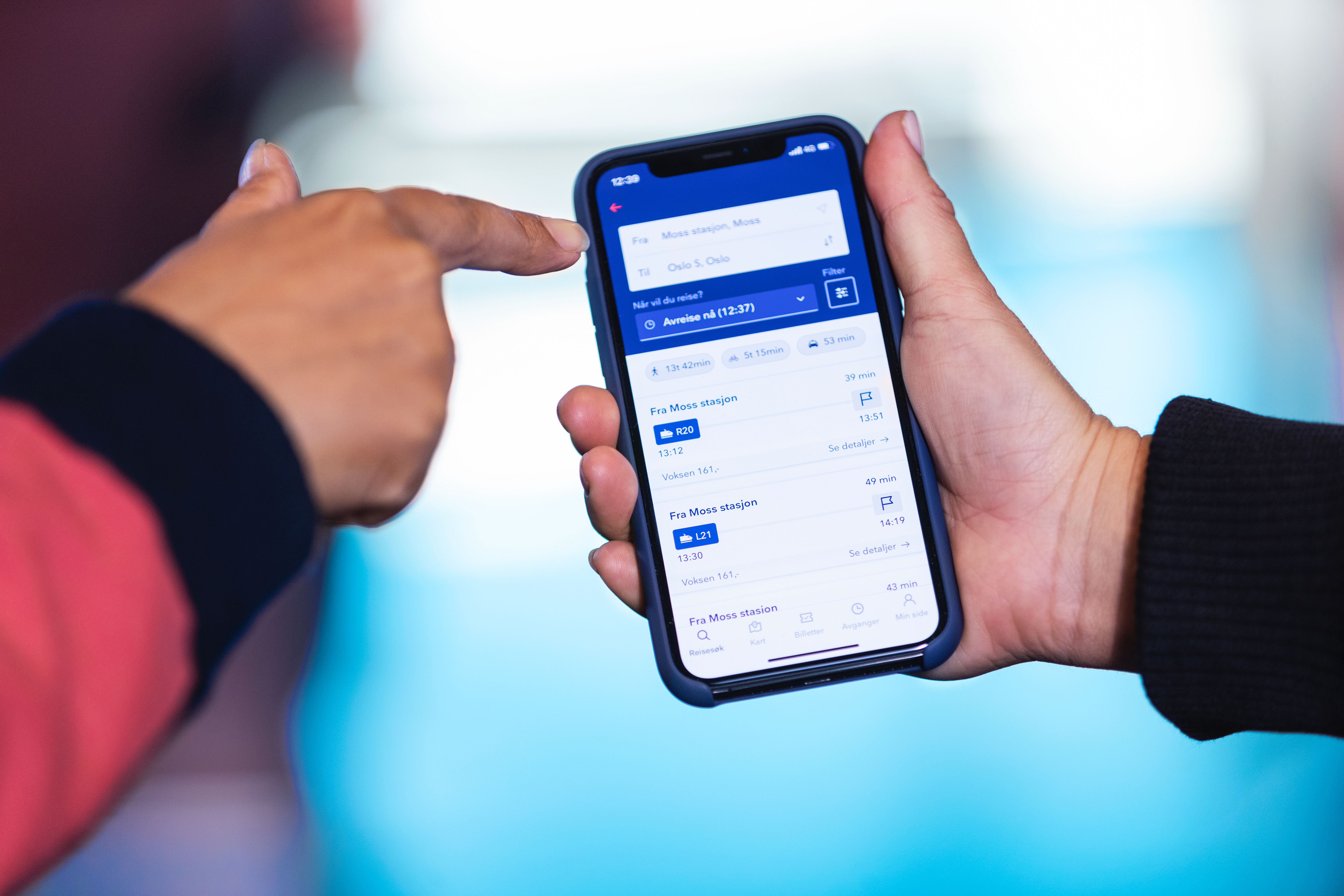 Kundeservice hjelper en reisende med å finne avganger i Entur-appen.