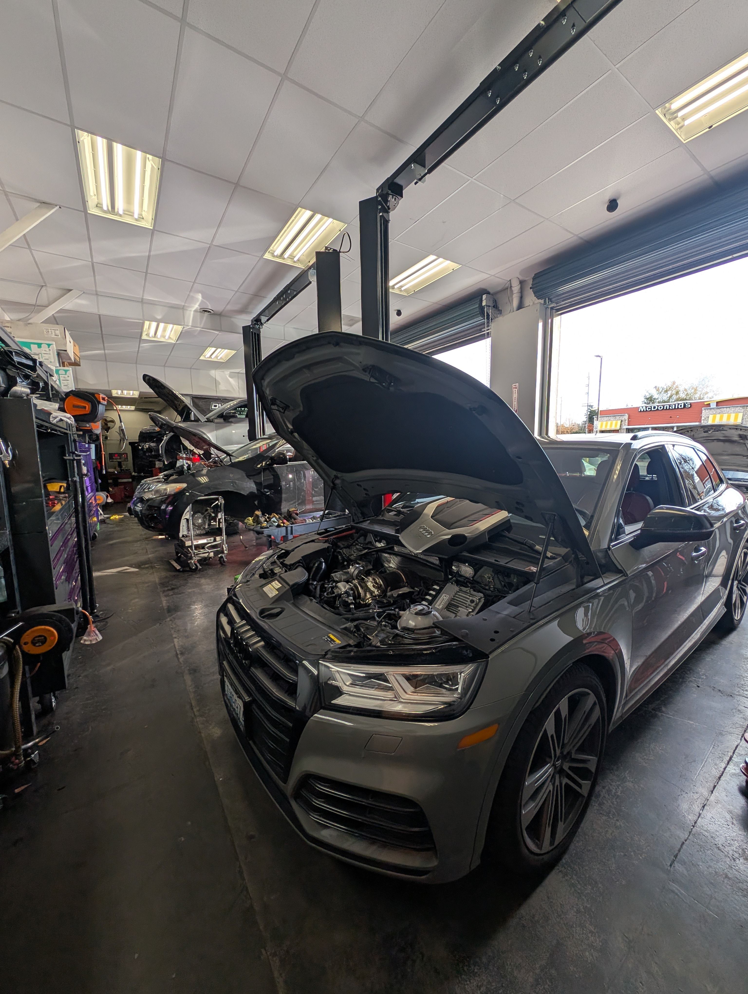 A view from inside the shop. A grey Audi SQ5 is parked in one of the vehicle bays.