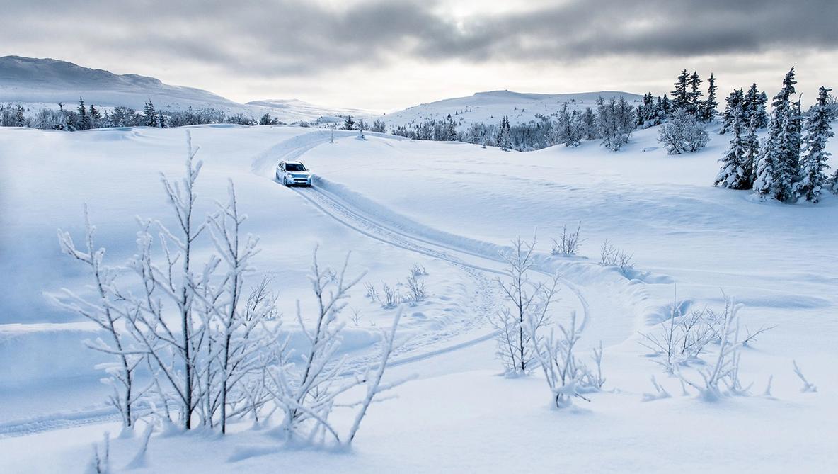 View of an electric vehicle driving on winter landscape