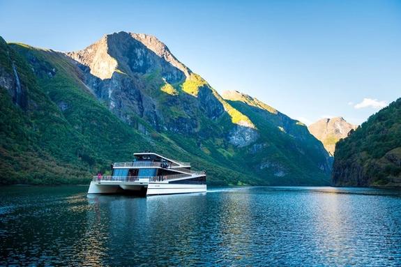 Electric ferry in Norwegian fjord with mountains behind