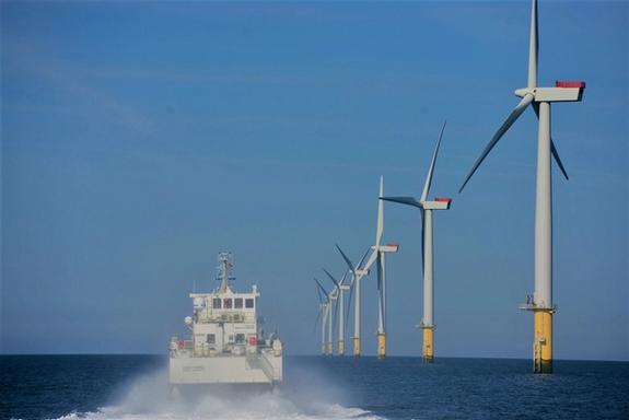 Photo of crew transfer vessel next to seven wind turbines in the ocean