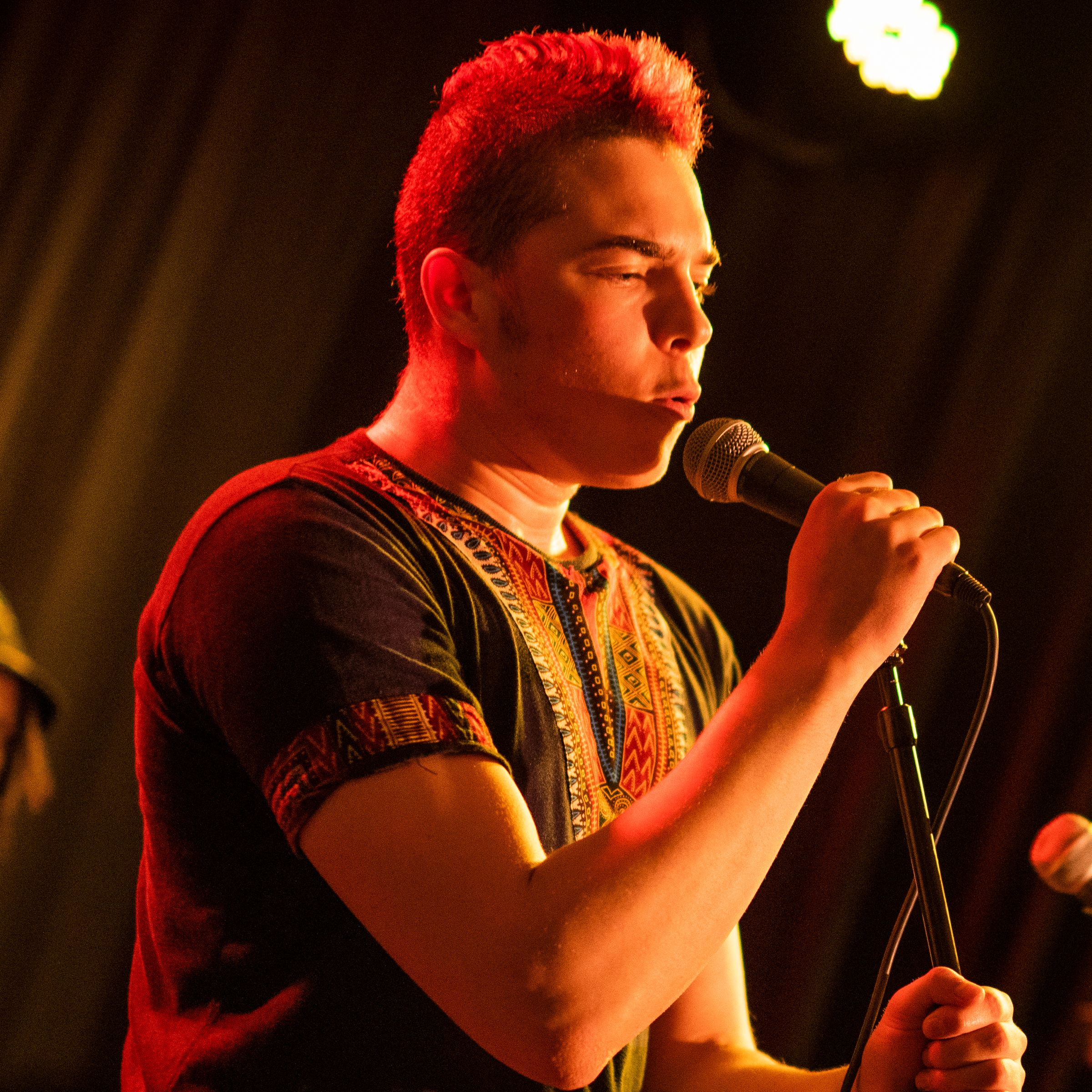 En kvinna sjunger på en scen med fin ljussättning