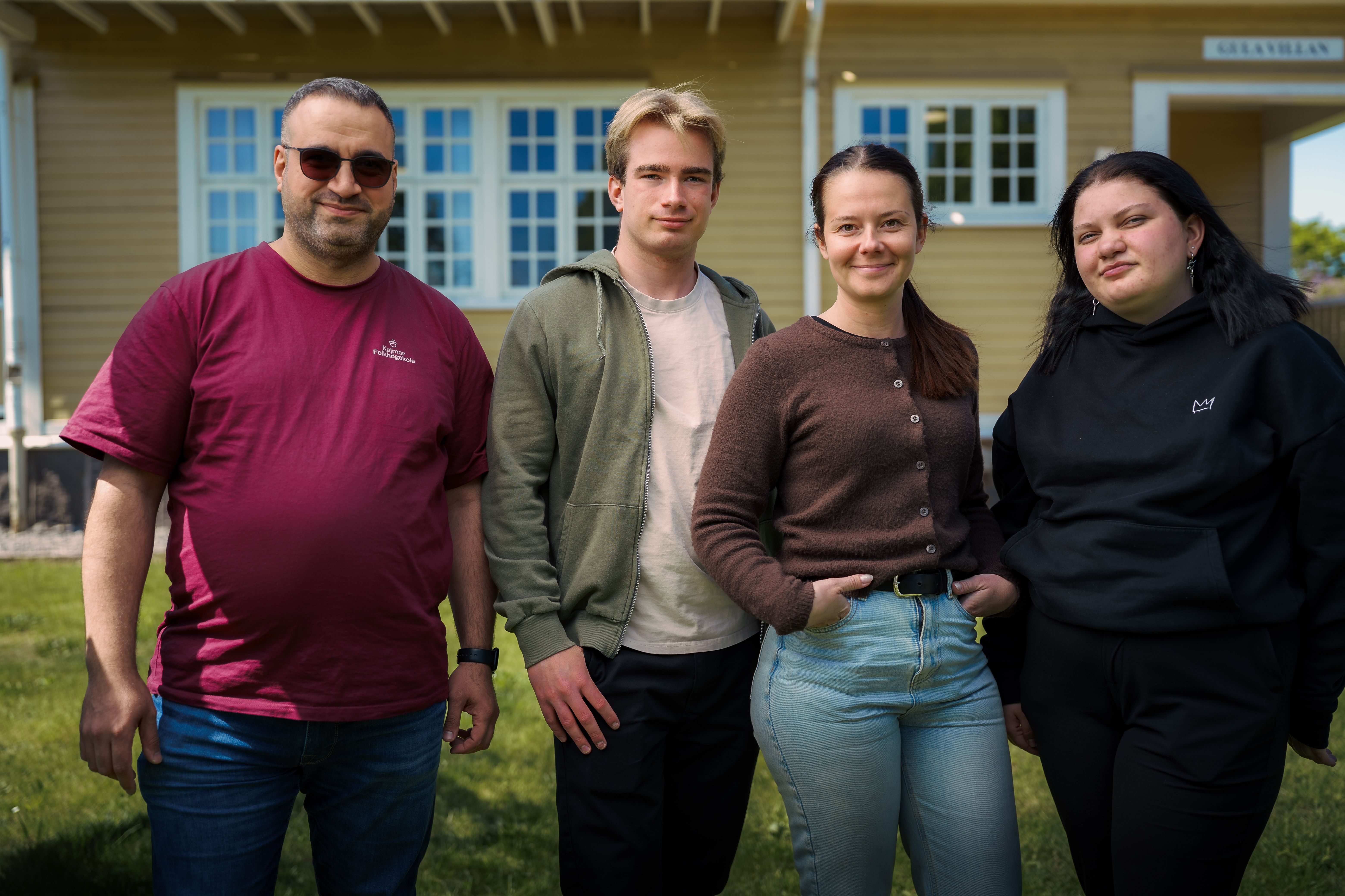 Fyra personer står bredvid varandra och ser glada ut