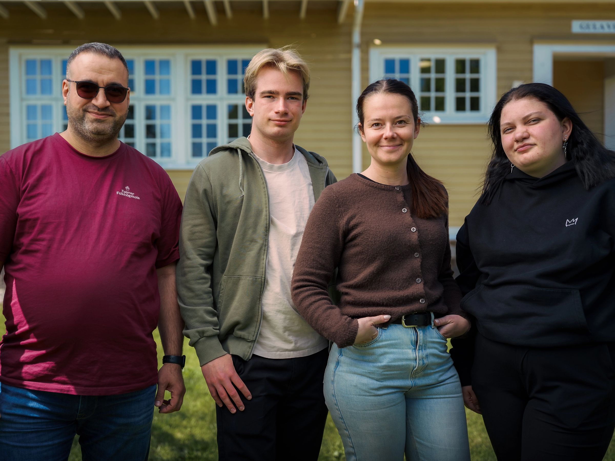 Fyra personer står bredvid varandra och ser glada ut