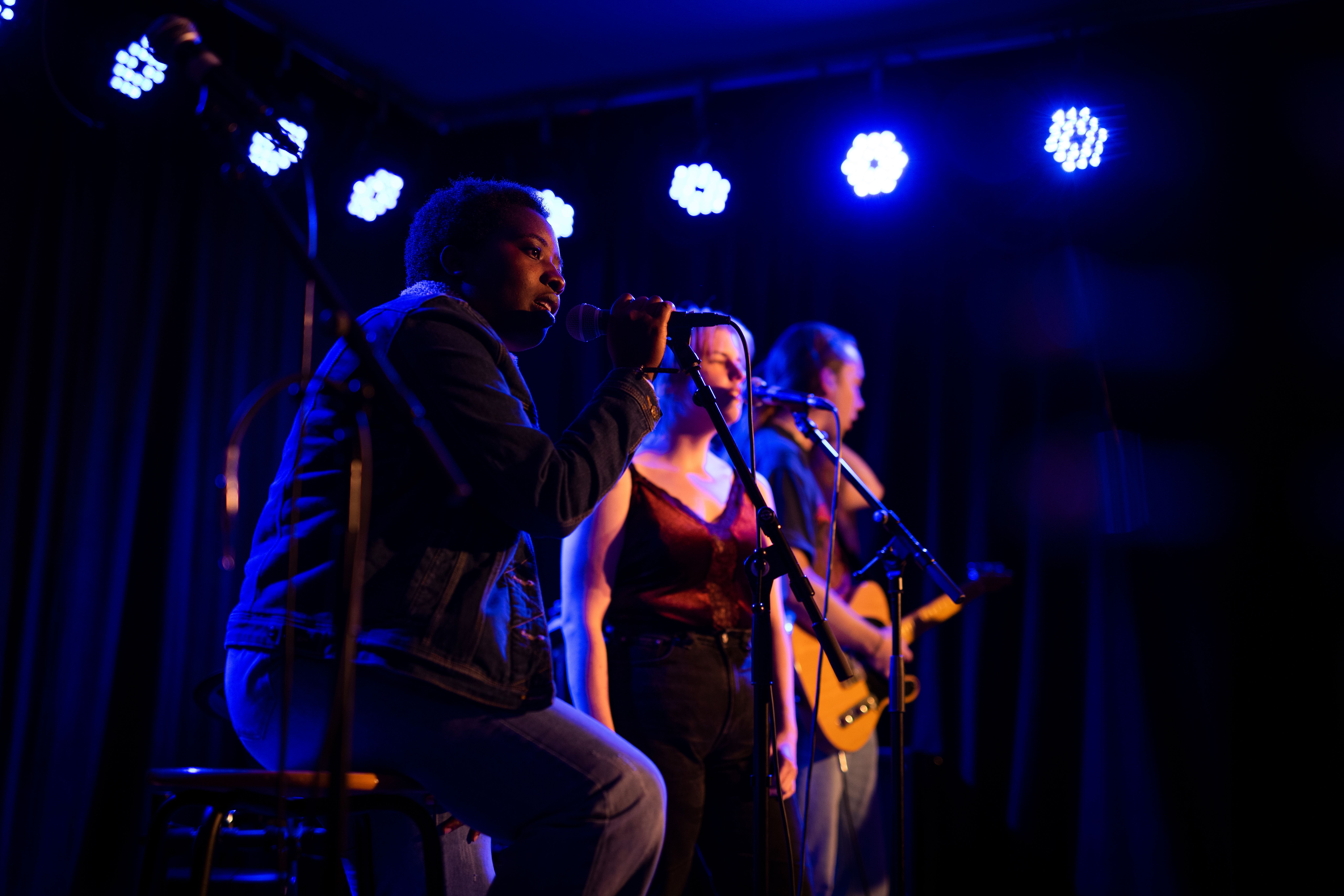 Deltagare framträder på scen under blått ljus.