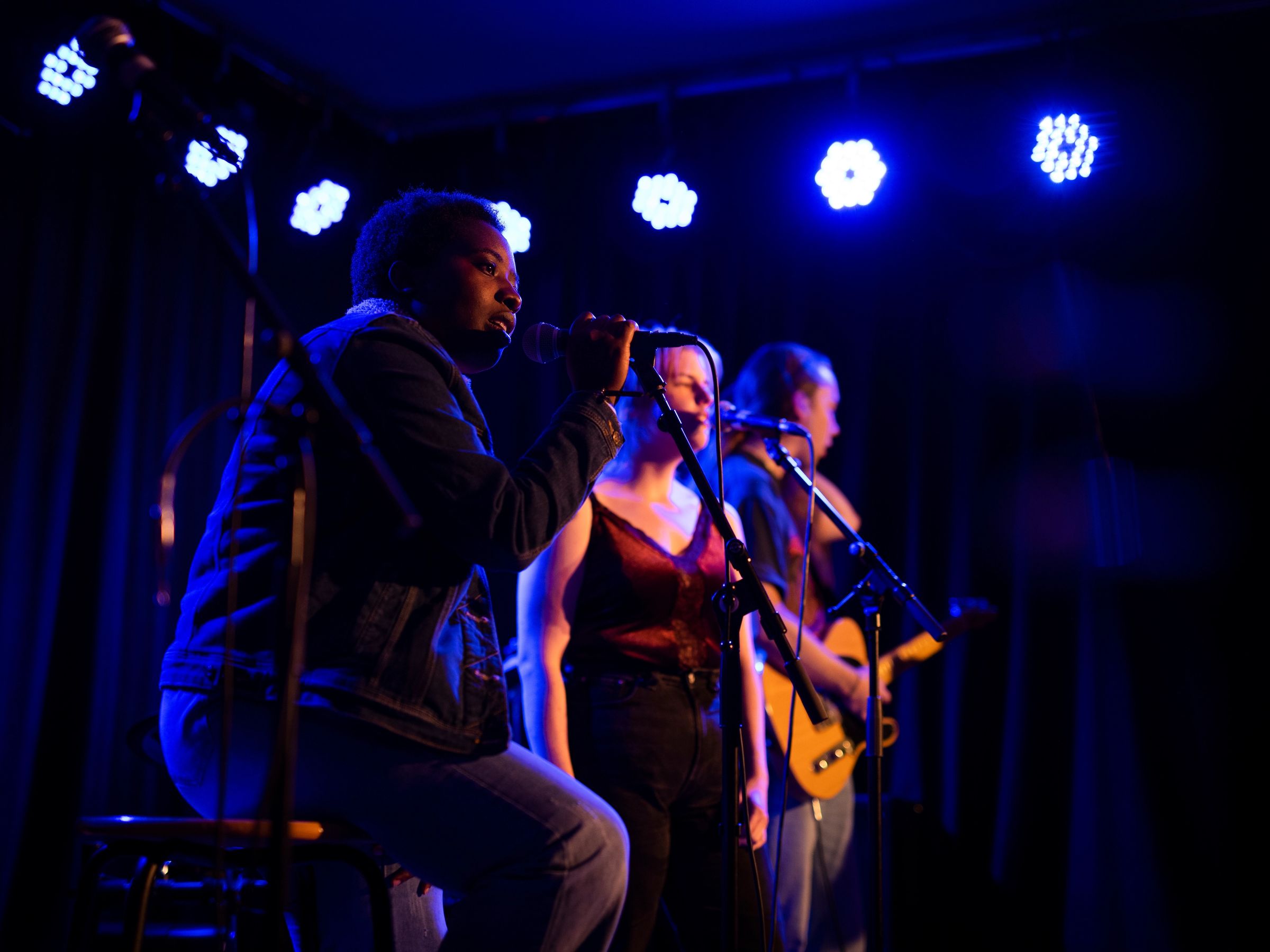 Deltagare framträder på scen under blått ljus.