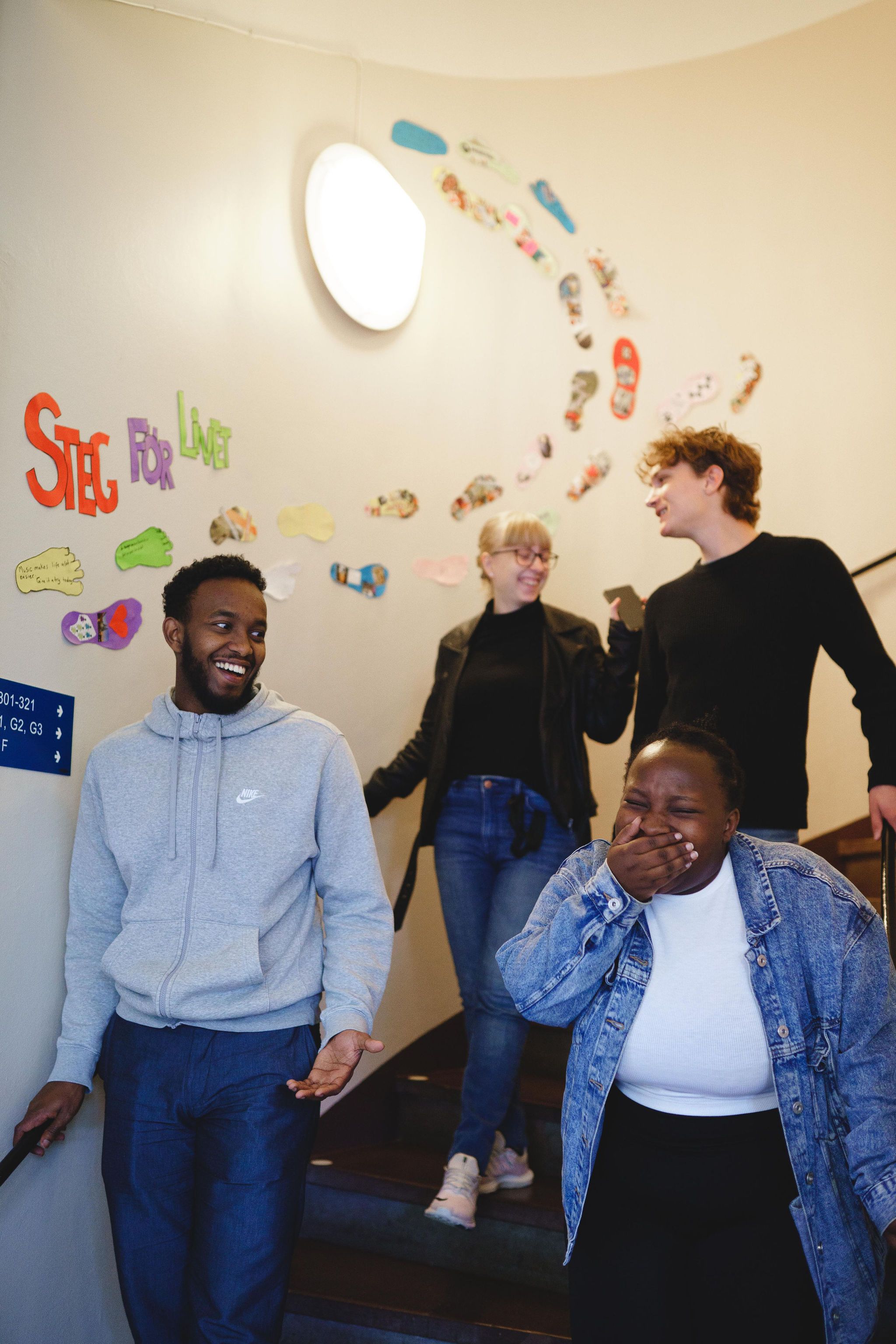 Fyra deltagare går ner för en trappa. De pratar och skrattar med varandra. 