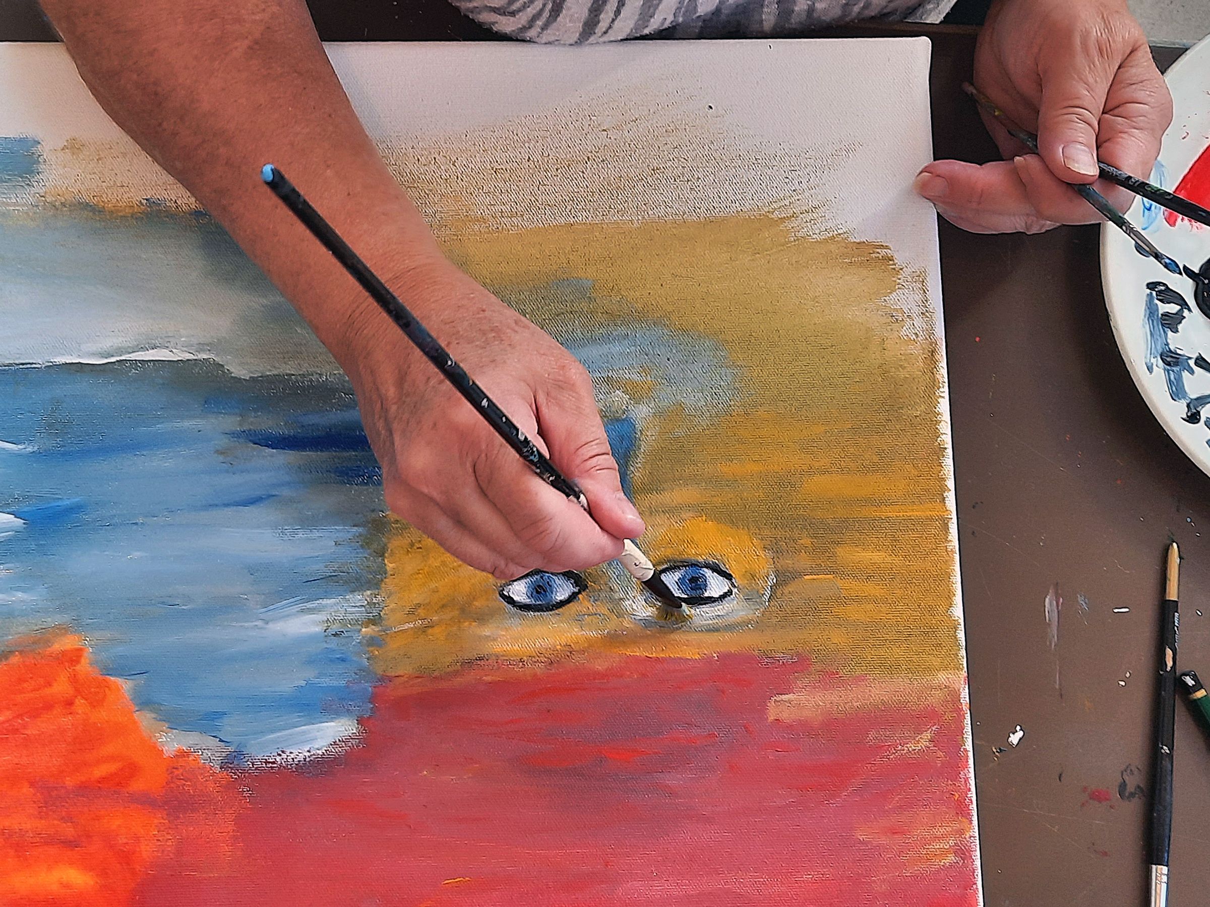 En hand målar ett öga på en canvas.