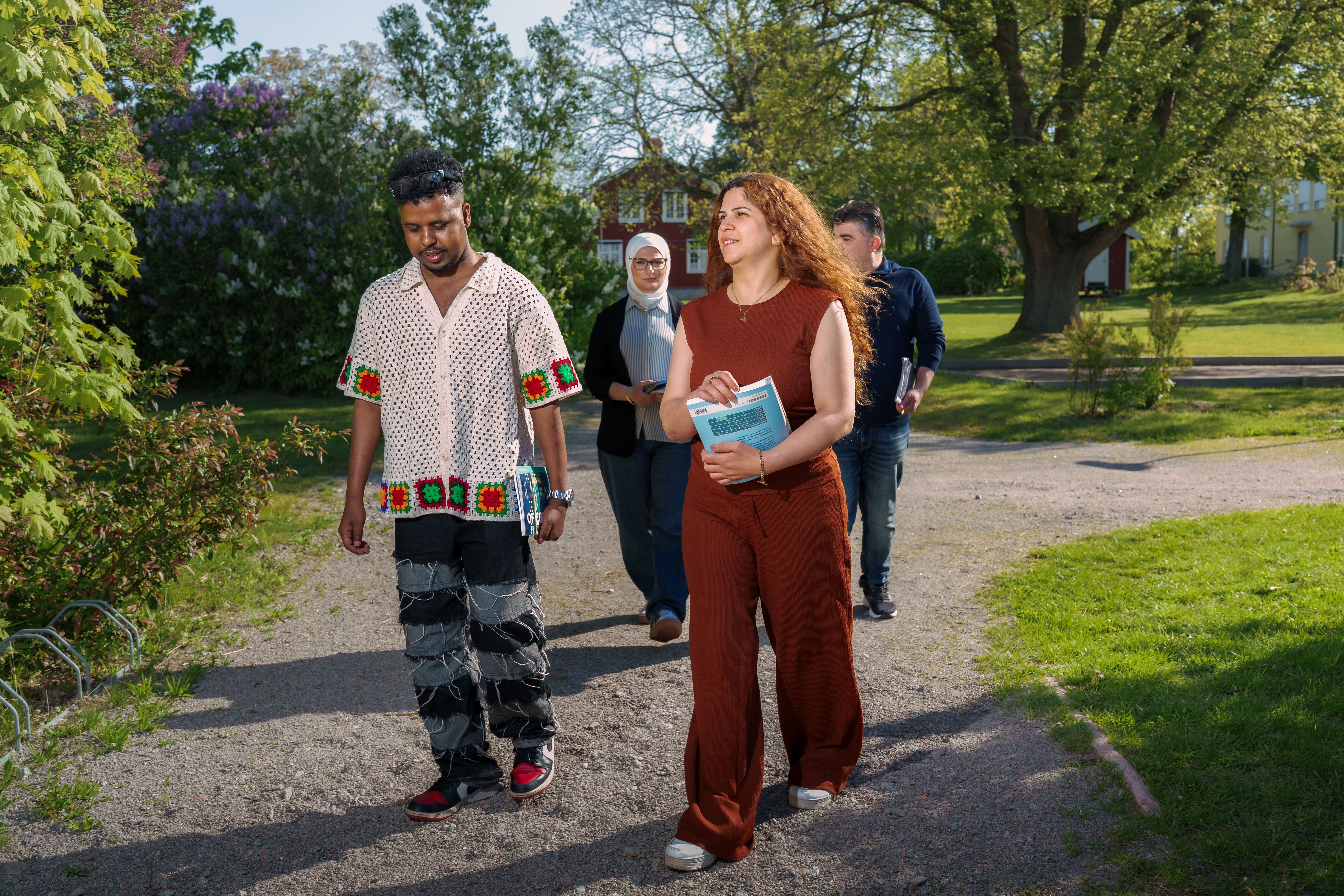 Fyra personer går på en stig, det är en varm och fin sommardag. 