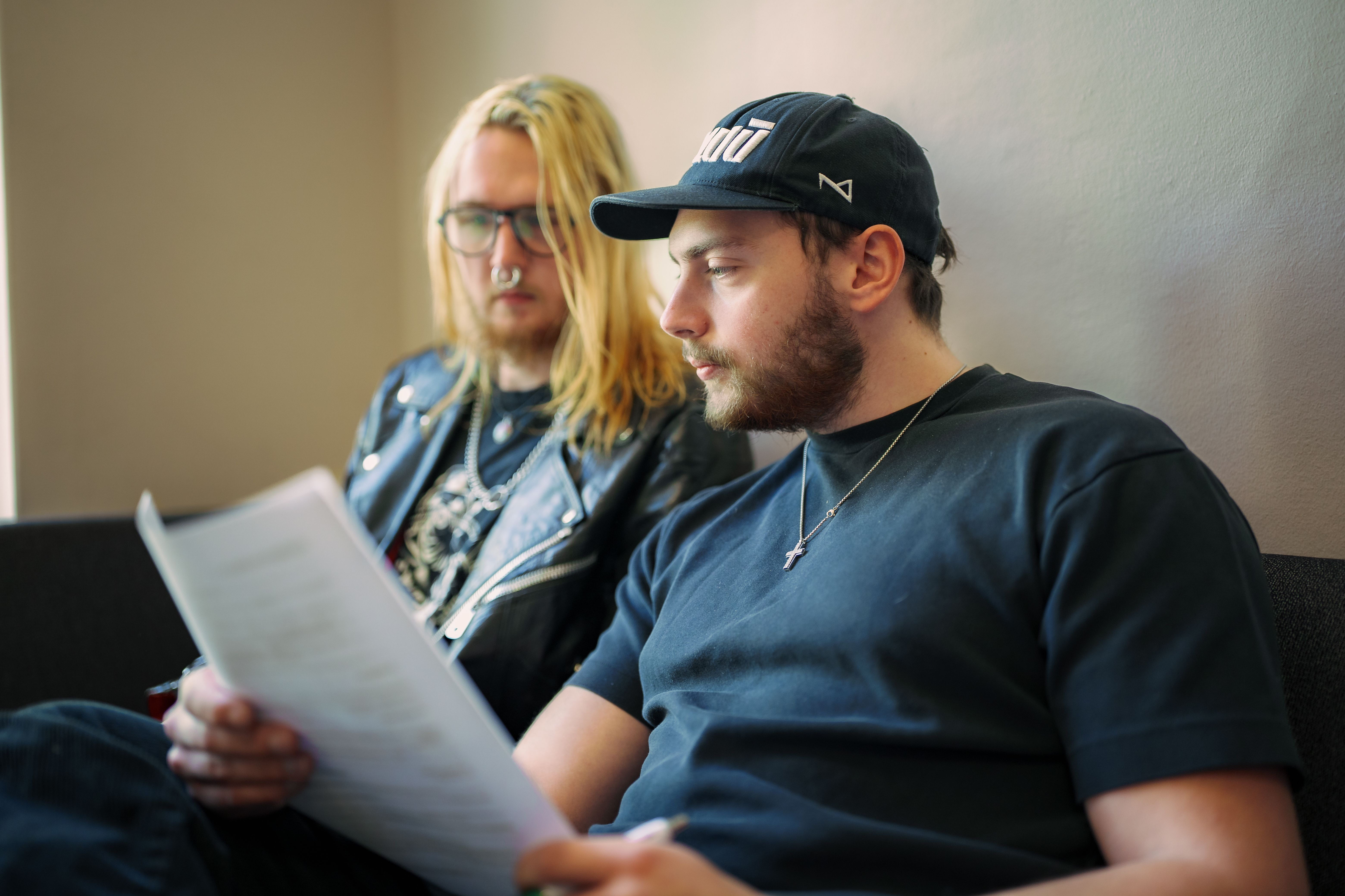 Tvä män i en soffa pratar med varandra och tittar på ett papper
