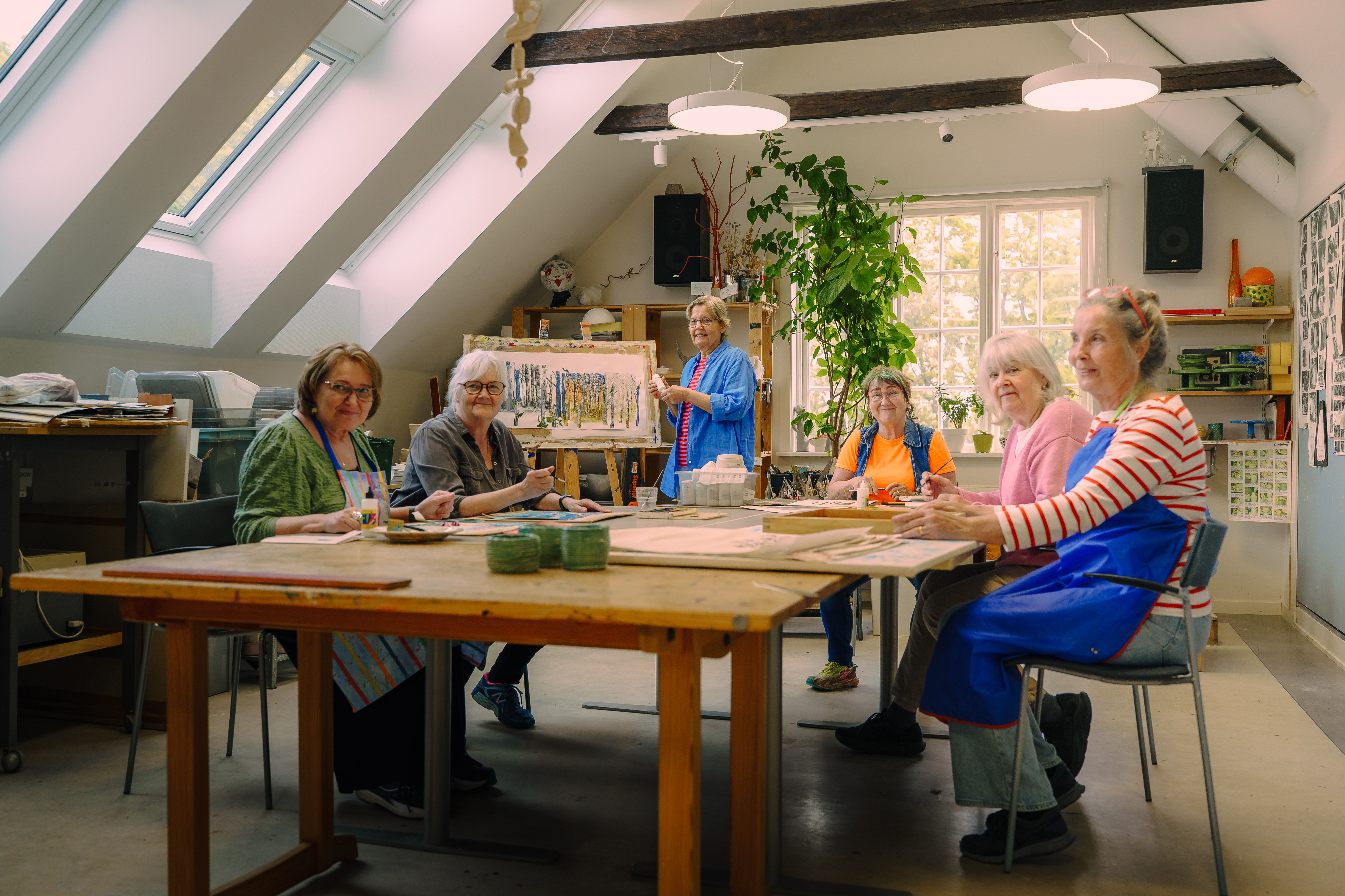 En grupp kvinnor sitter i ett ljust rum och målar.