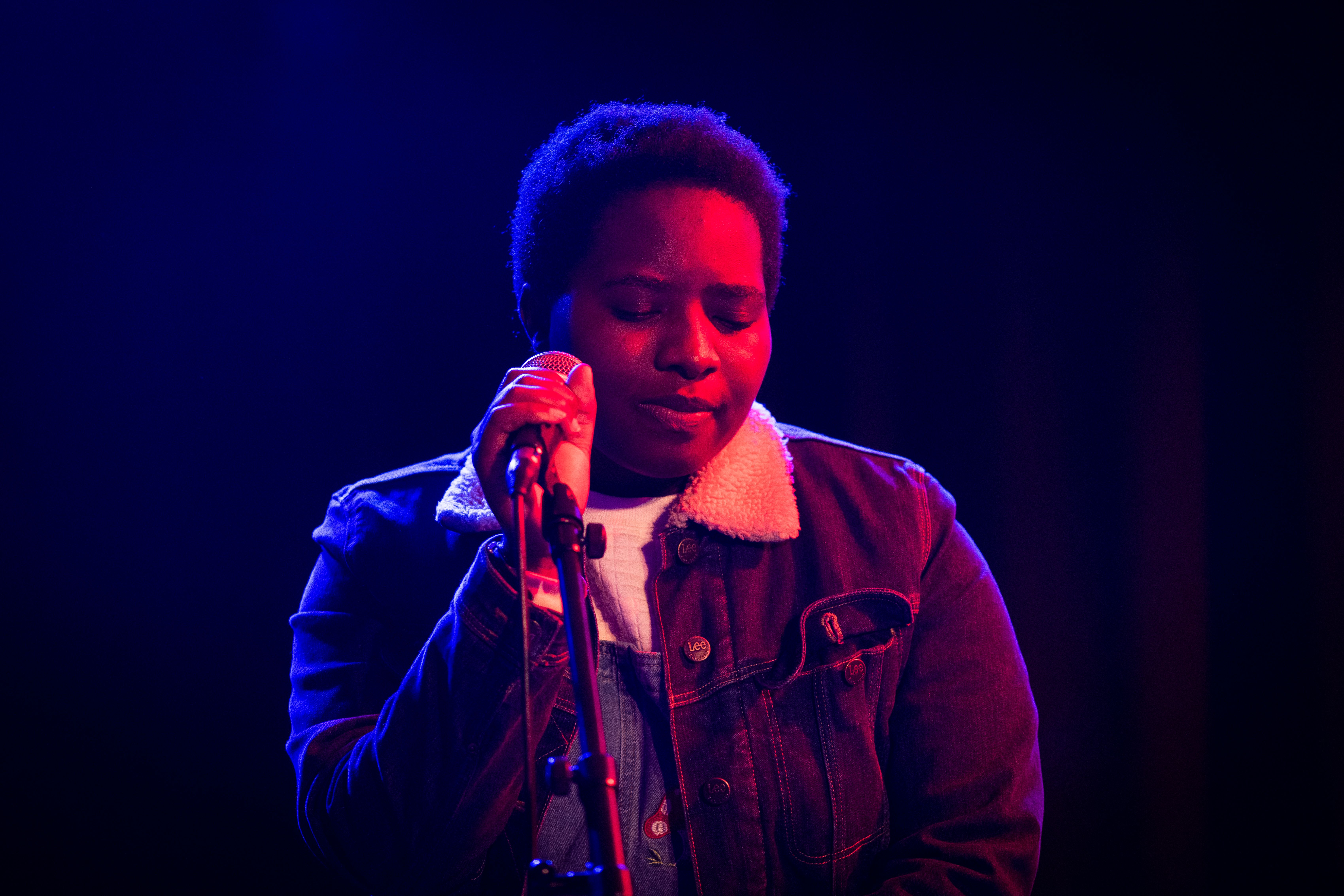 En kvinna sjunger på en scen med fin ljussättning