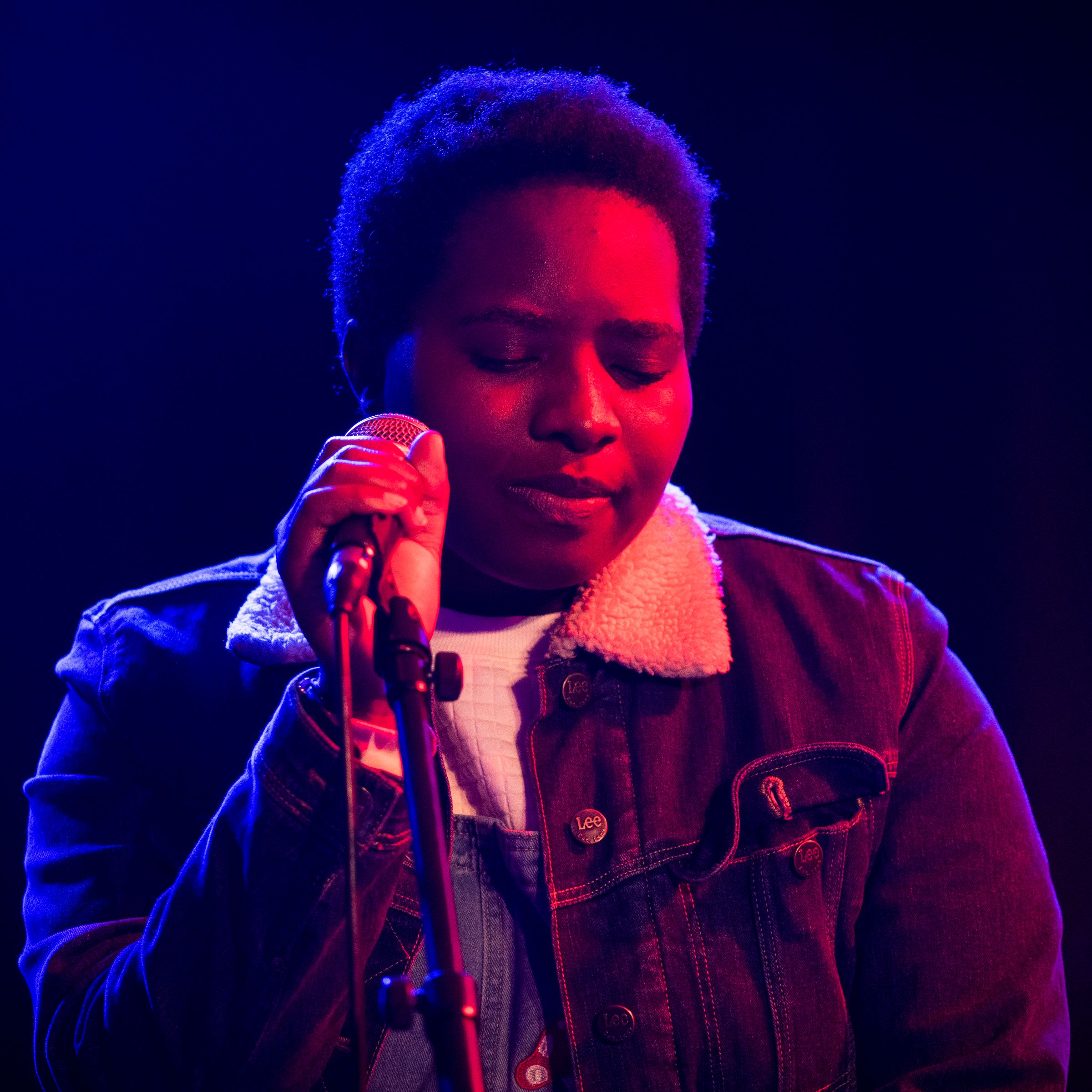 En kvinna sjunger på en scen med fin ljussättning