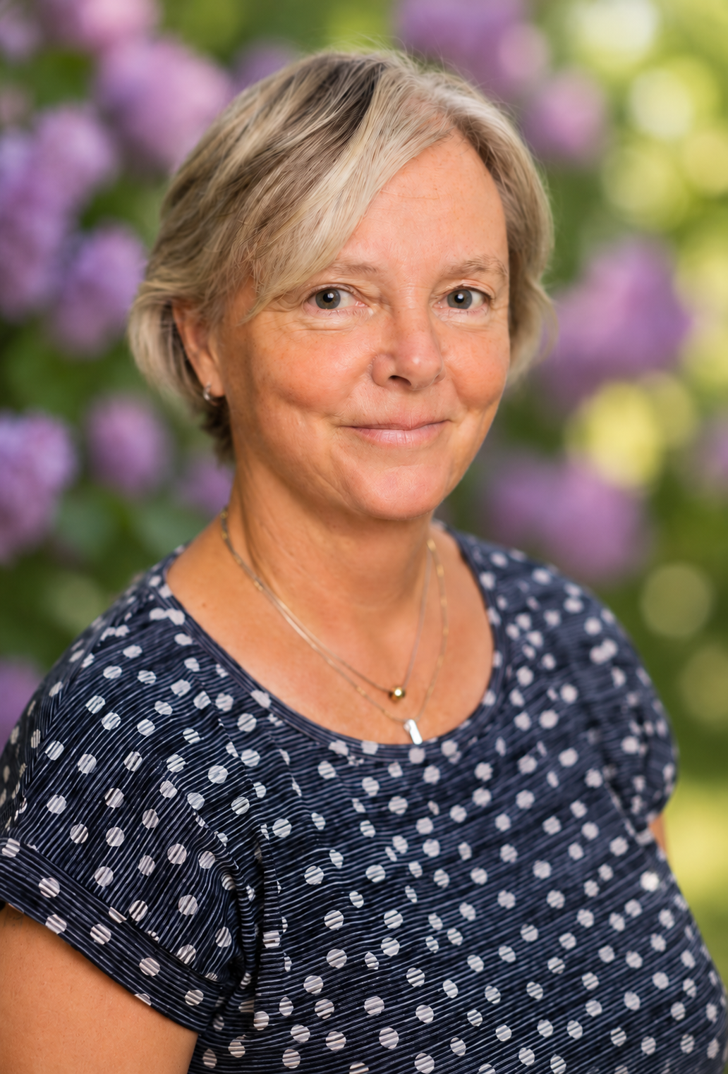 Foto på Monica framför en syrenhäck