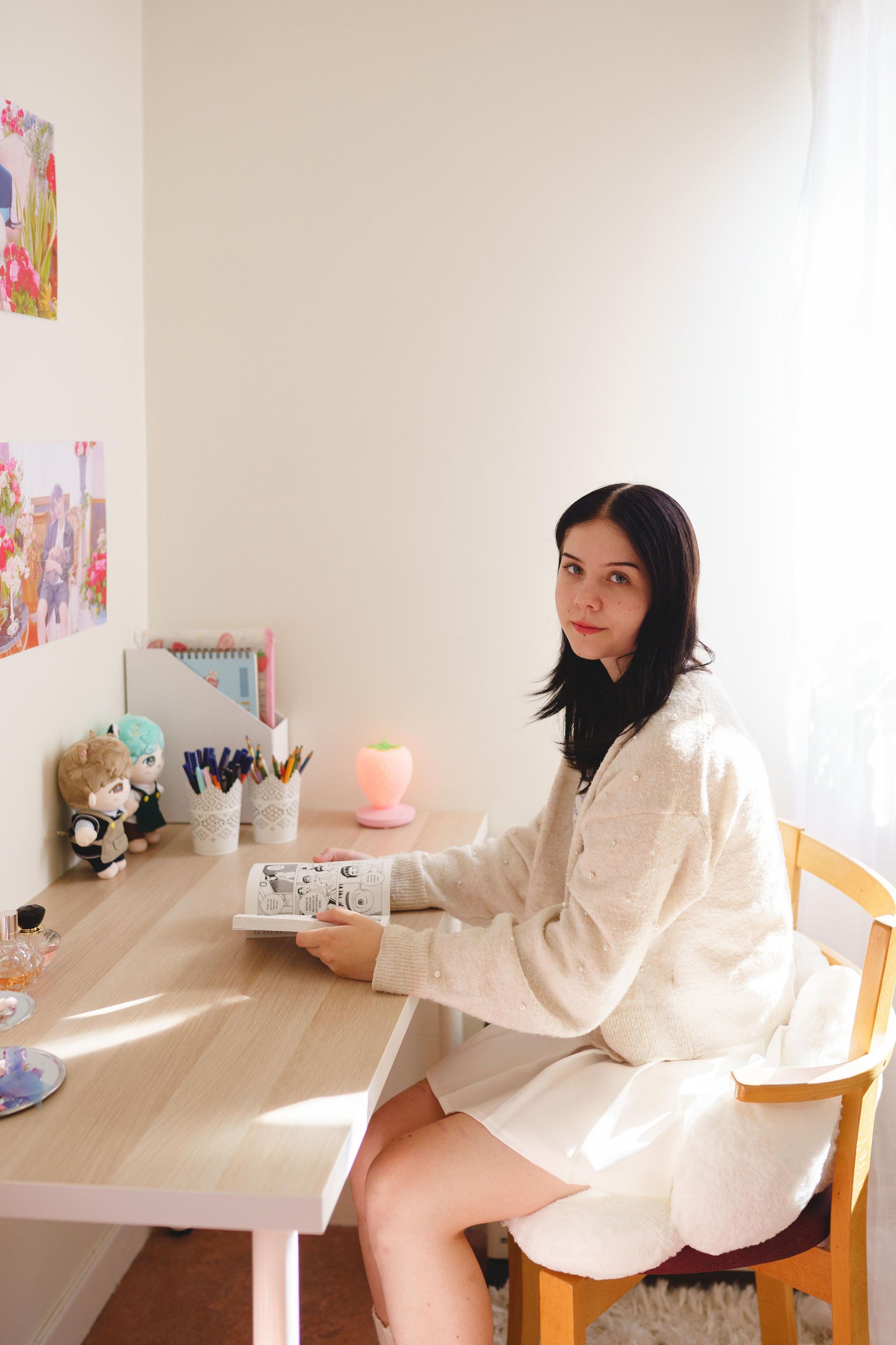 En tjej sitter vid ett skrivbord och läser en bok. 