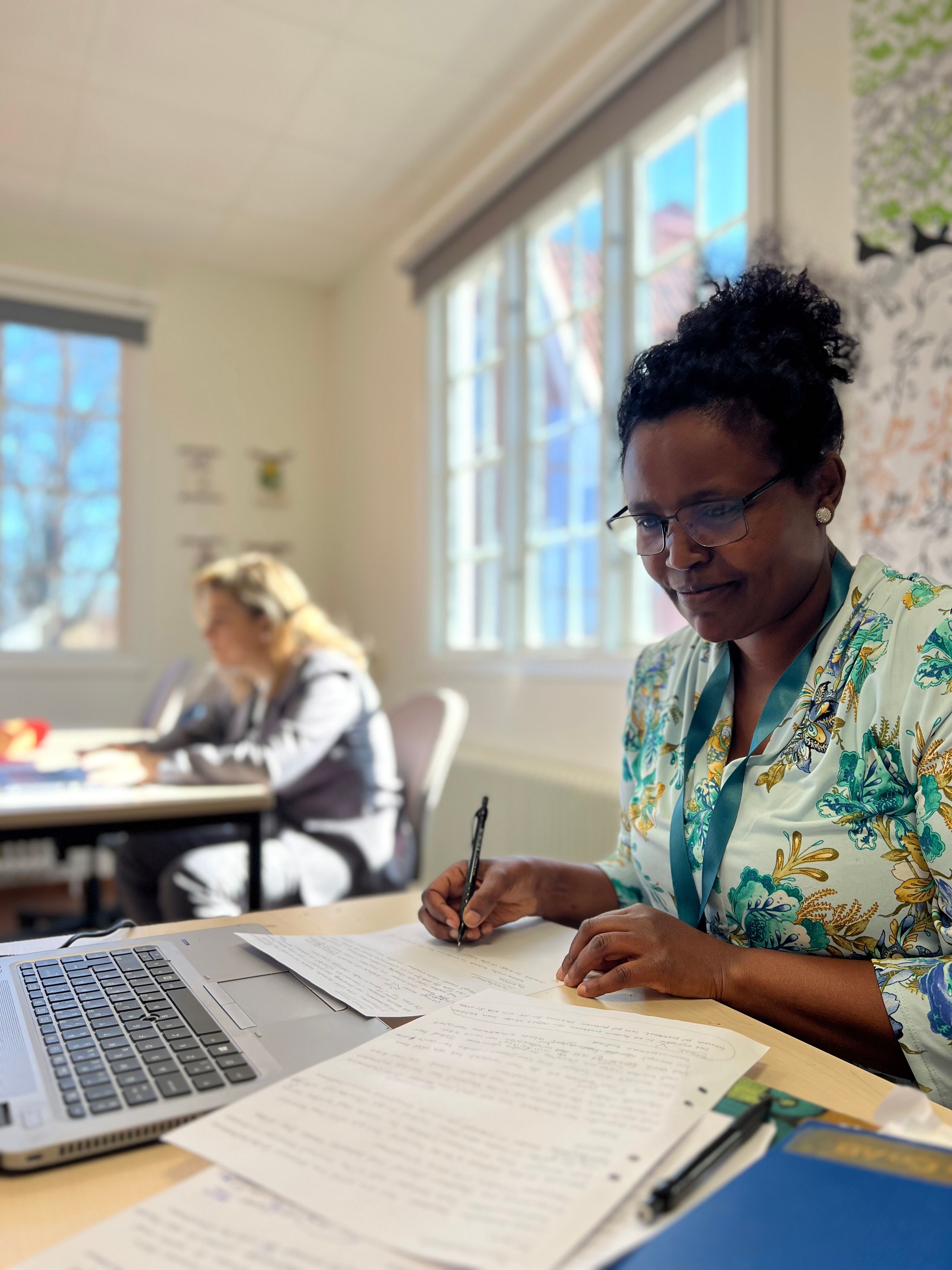 Två kvinnor studerar innehållet i en kursbok tillsammans. 