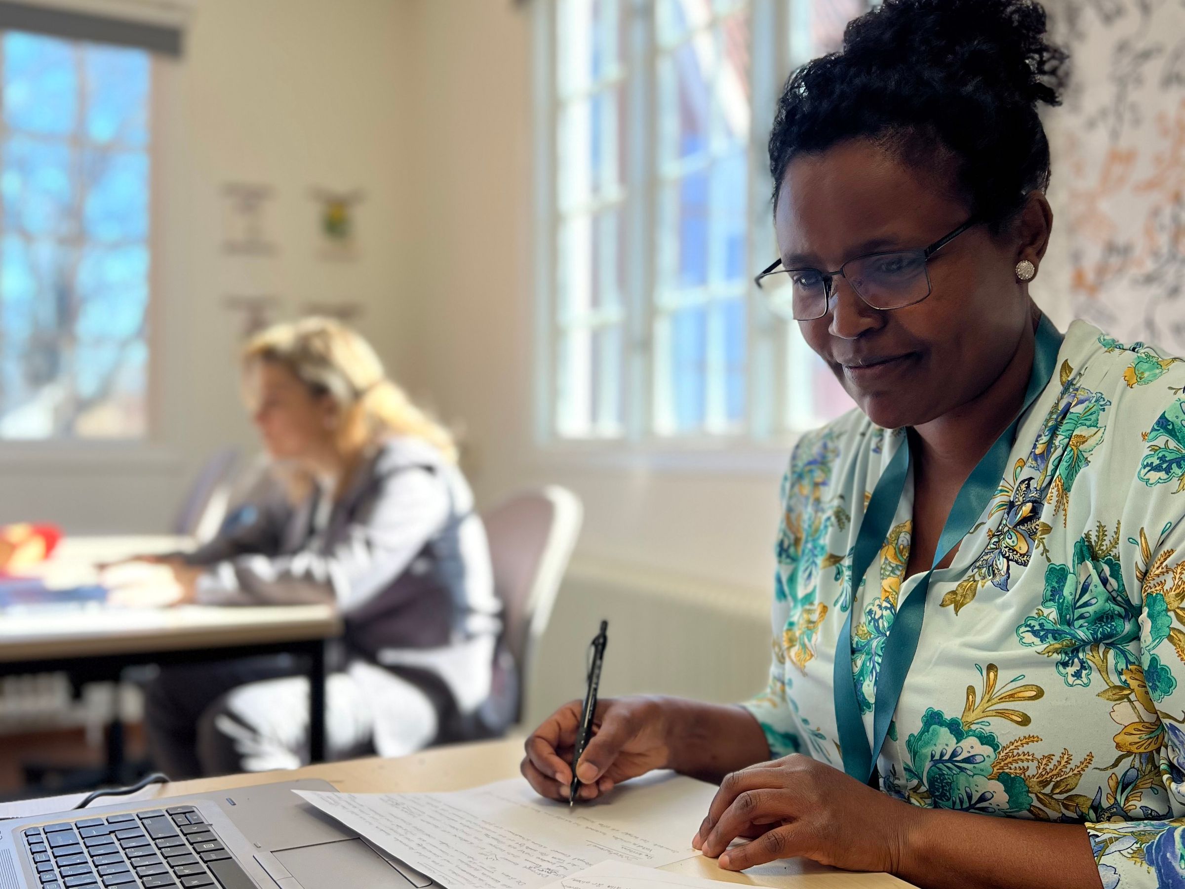 Två kvinnor studerar innehållet i en kursbok tillsammans.