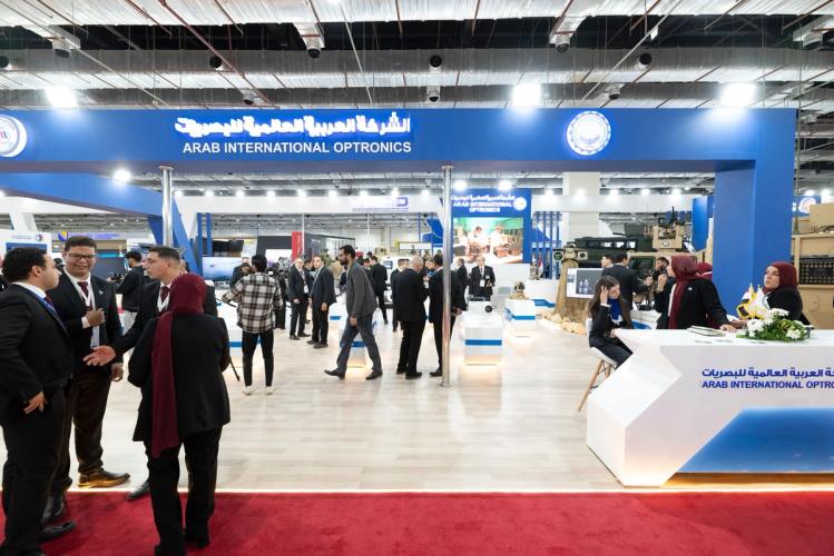 Delegates and exhibitors in conversation across a busy international defence exhibition floor
