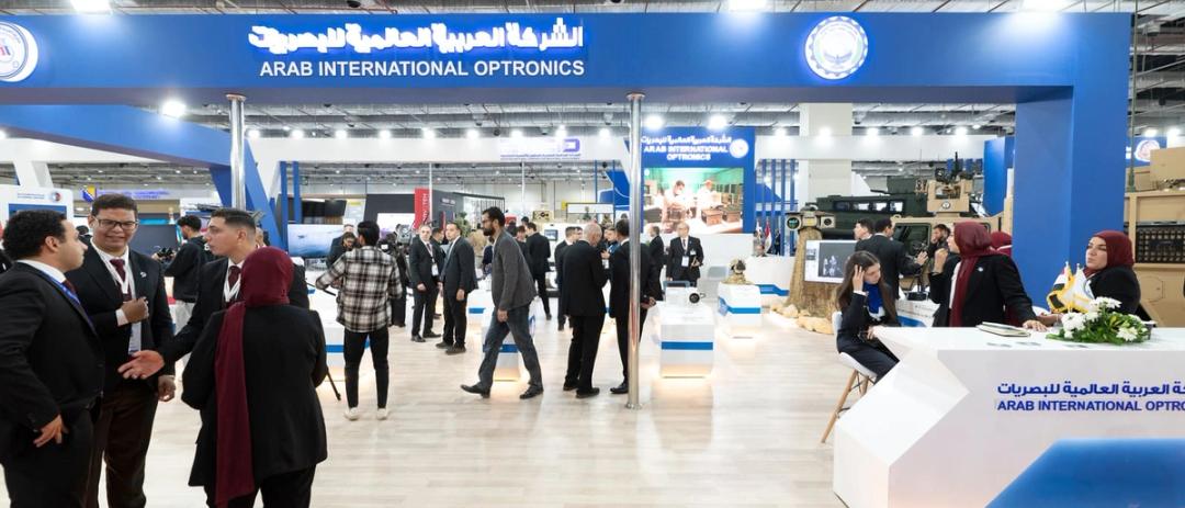 Delegates and exhibitors in conversation across a busy international defence exhibition floor