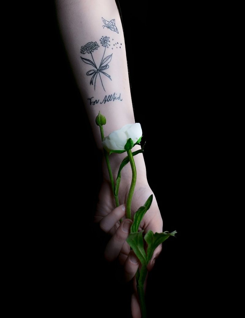 Delicate fine line butterfly and dandelion tattoo on inner arm