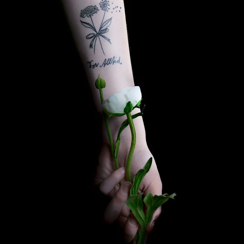 Delicate fine line butterfly and dandelion tattoo on inner arm