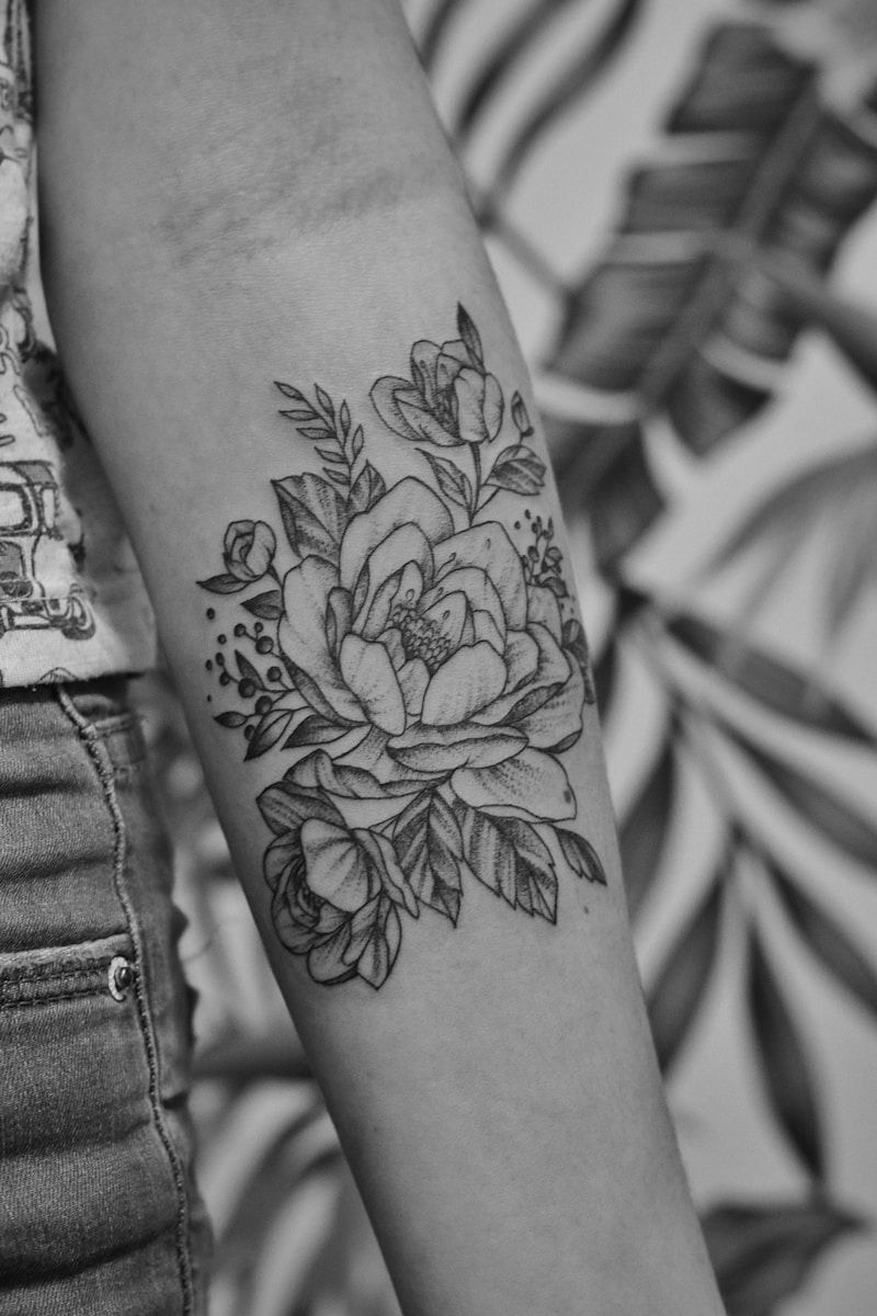 Fine line floral peony tattoo on forearm in black and white