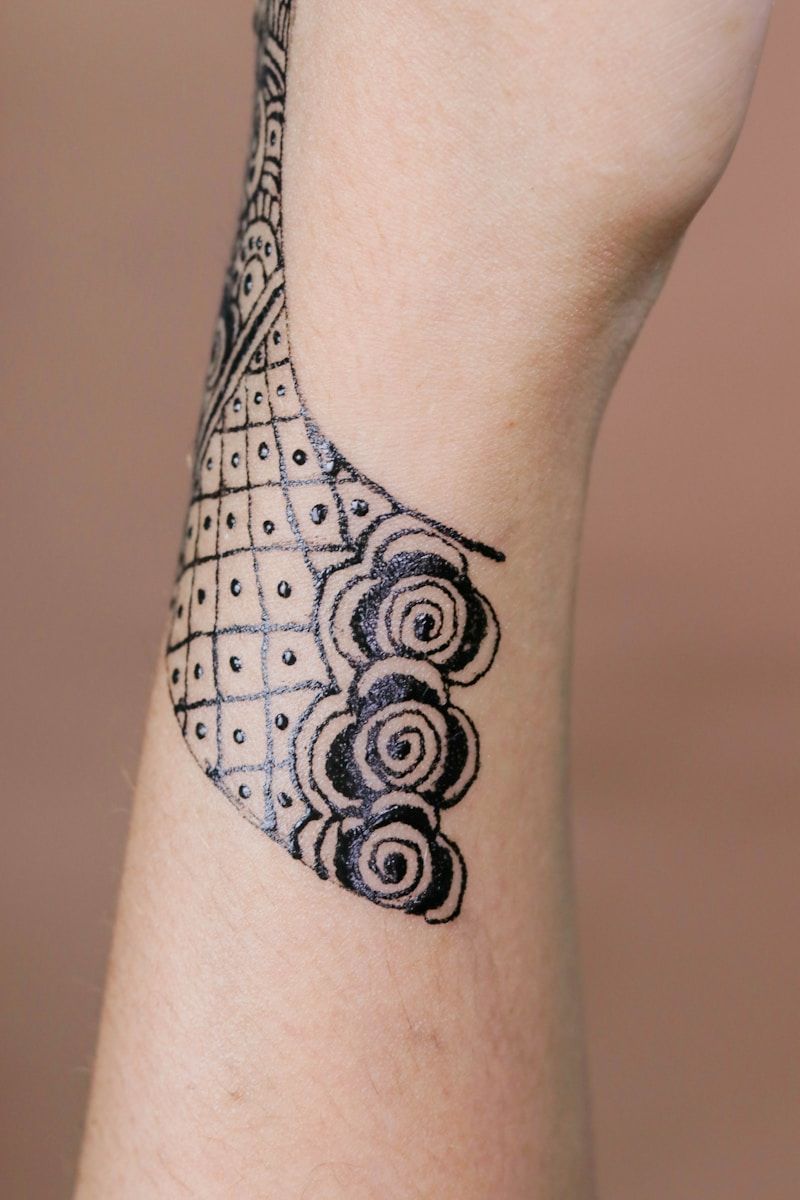 Geometric dotwork tattoo with grid pattern and spiral designs on wrist