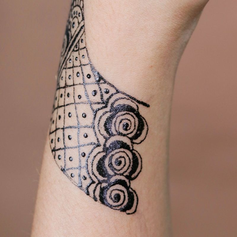 Geometric dotwork tattoo with grid pattern and spiral designs on wrist