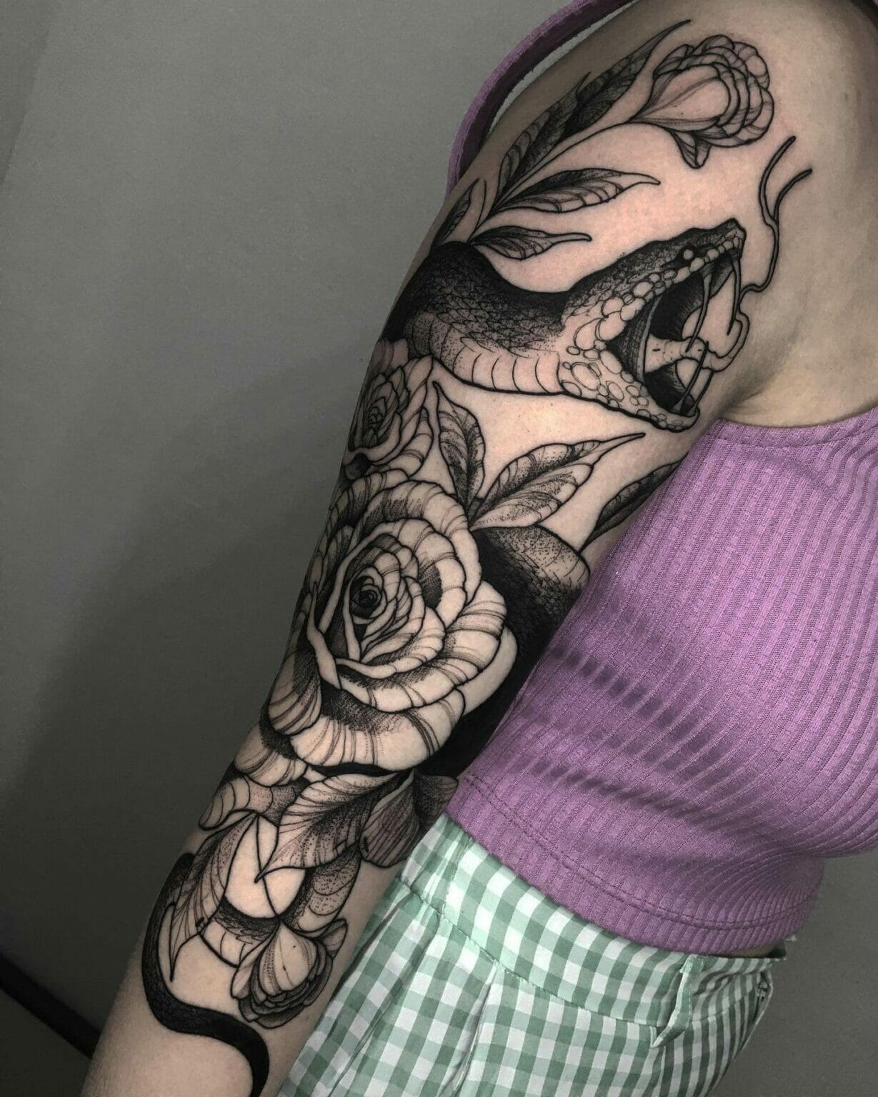 Detailed snake tattoo wrapping around upper arm with bold shading