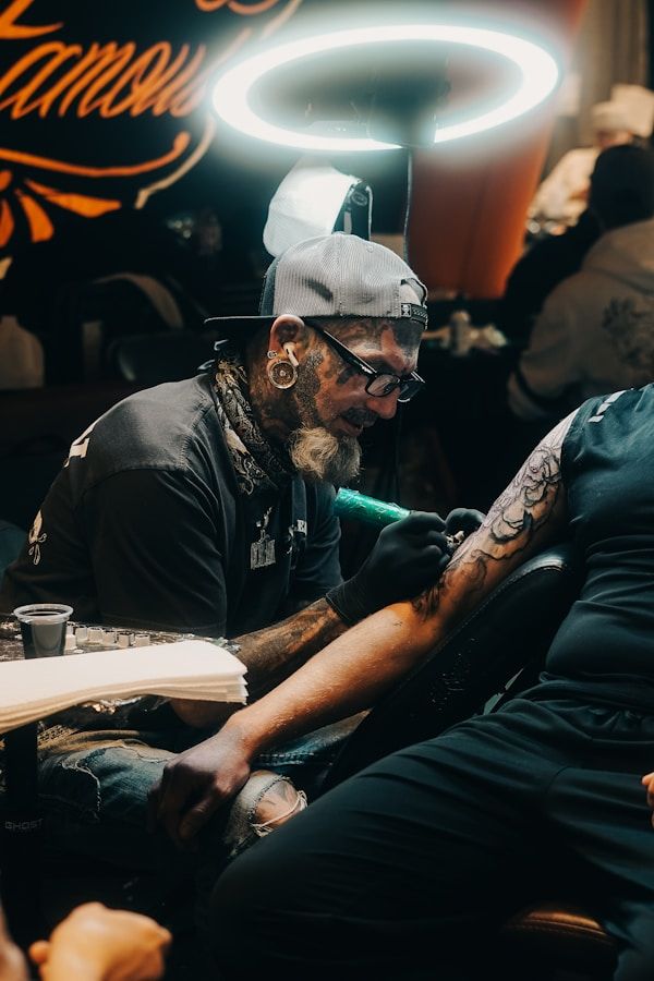 Tattoo artist working on a client arm in a professional studio