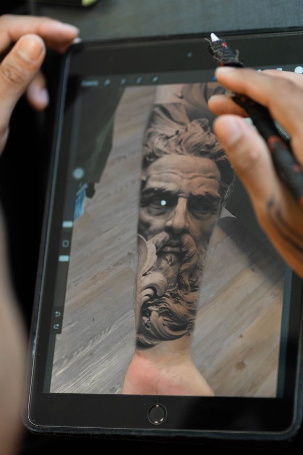 Tattoo artist using digital tablet to design custom tattoo with client