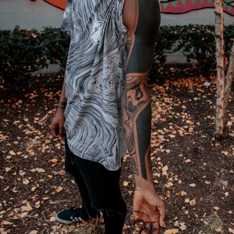 Full blackwork sleeve tattoo with flowing abstract design on arm