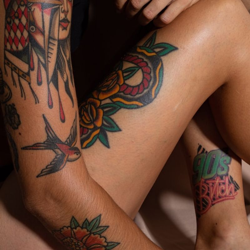 Neo-traditional colourful leg tattoos with bold outlines featuring roses, swallows, and hourglass motifs