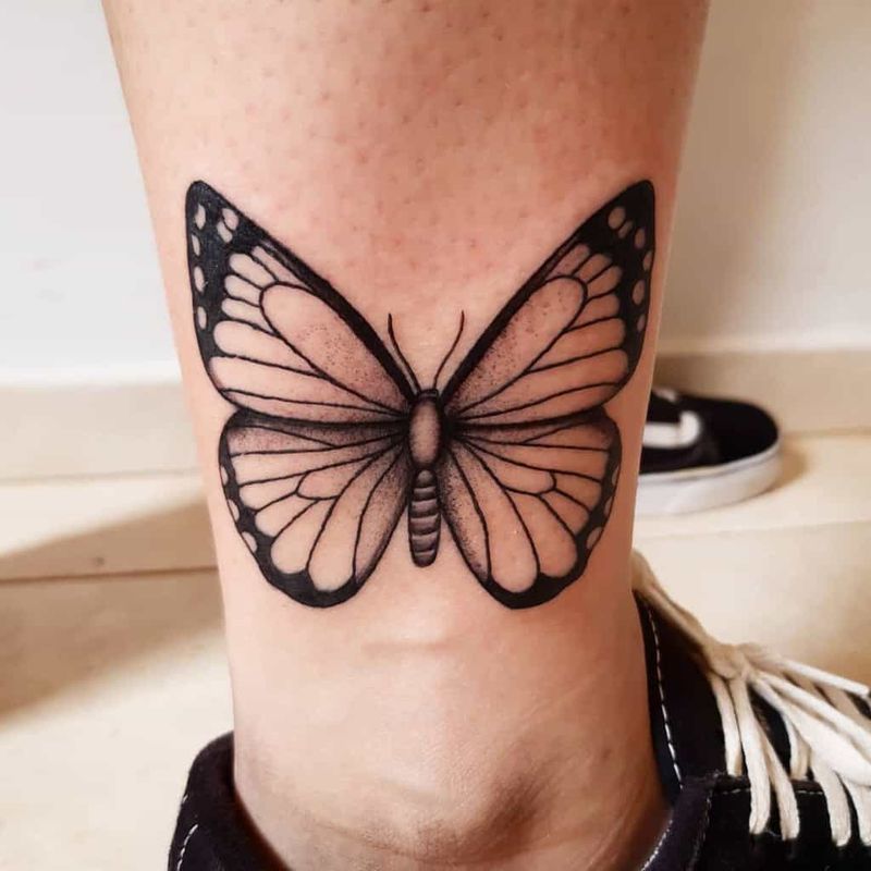 Bold butterfly tattoo design with dark shading and contrast on arm