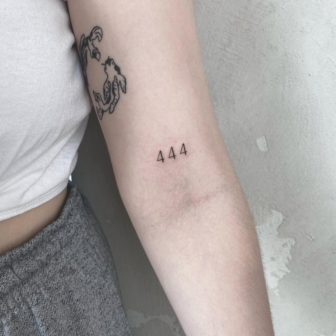 Minimalist 444 angel number tattoo in black ink on inner arm