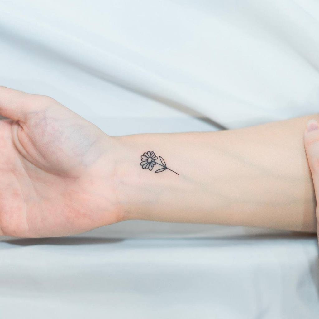 Small minimalist flower tattoo on wrist — perfect first tattoo idea