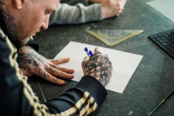 Tattoo artist sketching a custom design during client consultation