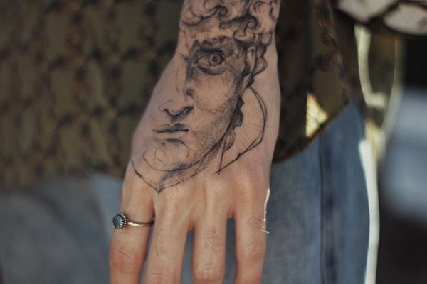 Realism black rose tattoo with detailed shading on forearm
