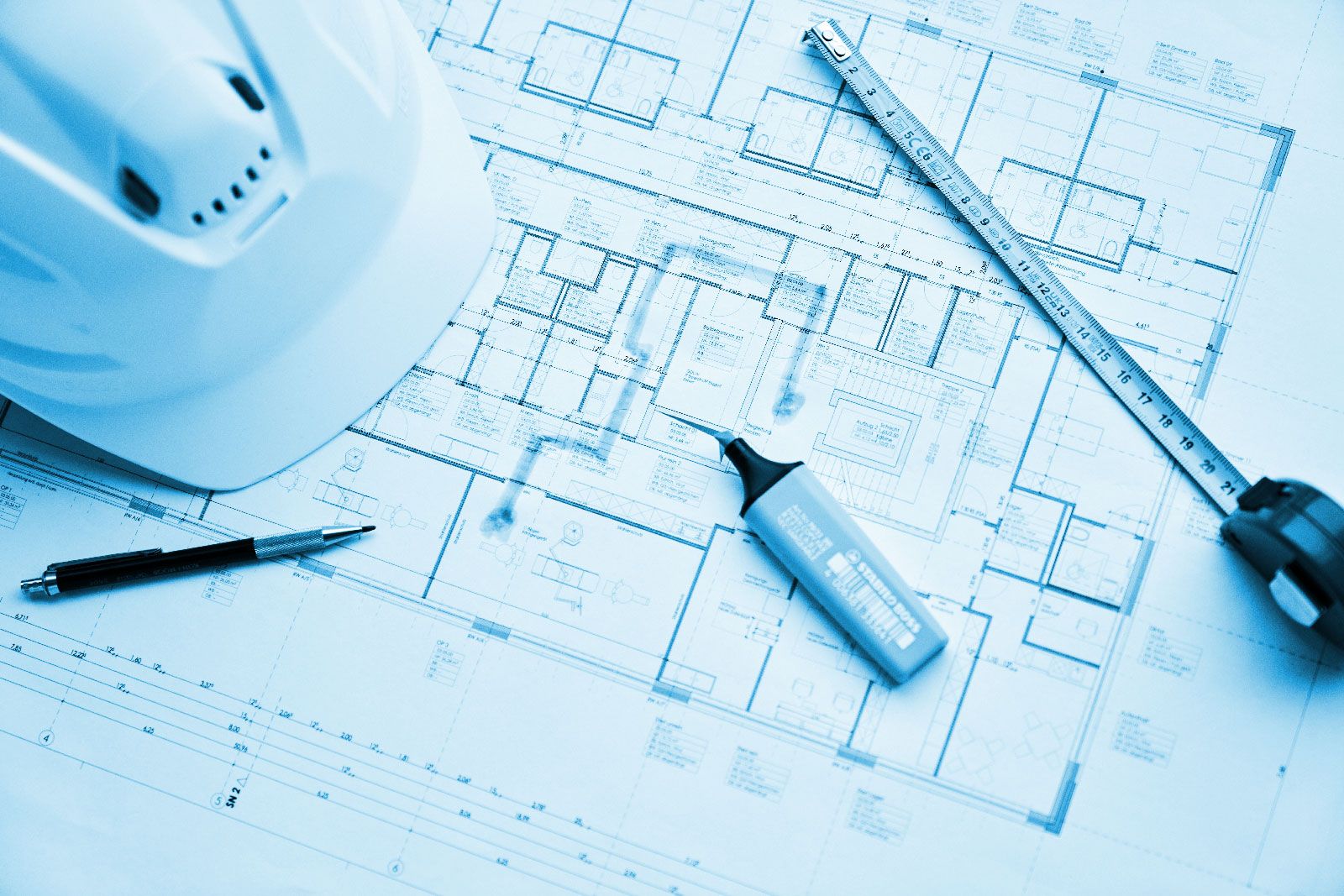 Rinke + Henssler Blogbeitrag Bild – Bauplan mit Helm, Kugelschreiber, Textmarker und Maßband. Blau eingefärbt.
