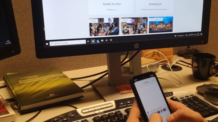 Nærbilde av en som skriver SMS foran en datamaskin.