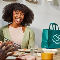 a woman is sitting at a table eating food with chopsticks .