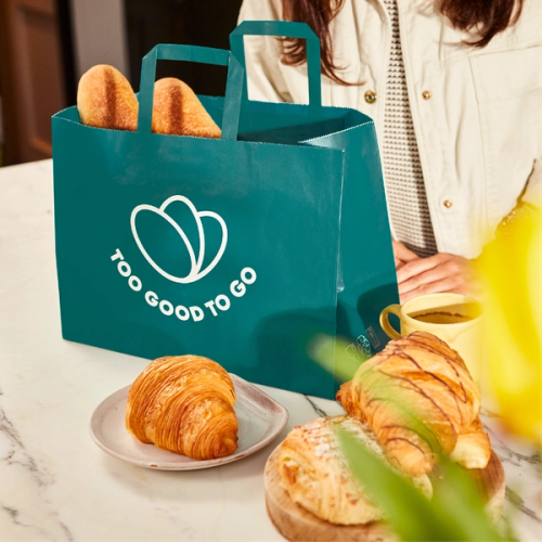 a woman is putting a croissant on a table while another woman looks on .