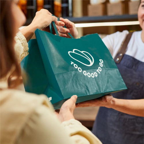 a man is giving a green bag to a woman in a store .