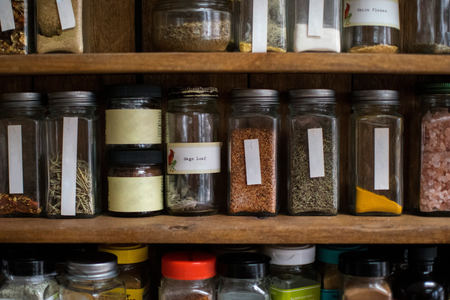 A jar of sage leaf sits on a wooden shelf.