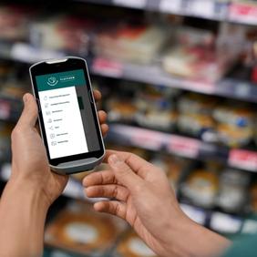 a person is holding a cell phone in a grocery store .