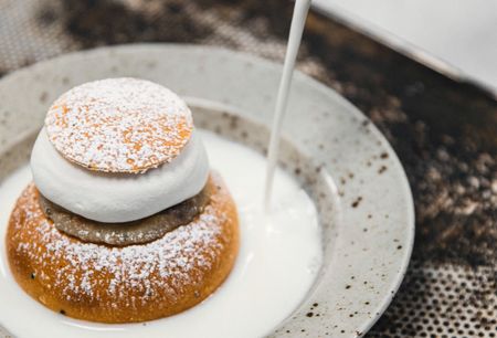 a close up of a semla on a plate with milk being poured on it
